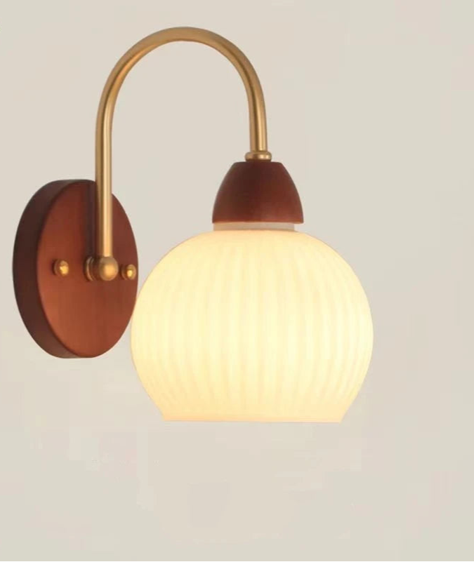 Wall-mounted light fixture with wooden base and gold arm on a plain background