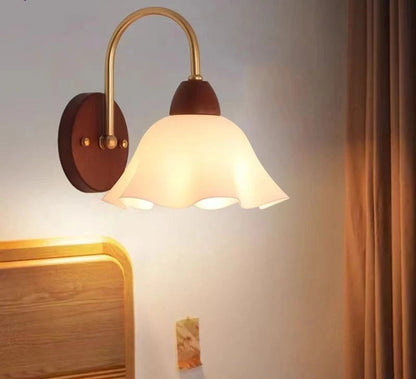 Wall-mounted lamp with a brown base and gold arm on a light gray wall.