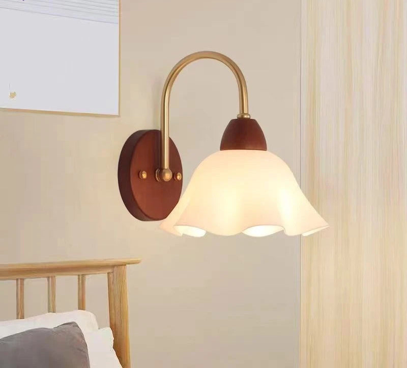 Wall-mounted lamp with brown base and white shade in a bedroom setting.